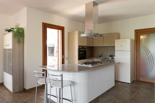 Una cocina moderna con una isla central, electrodomésticos de acero inoxidable y vistas al exterior.