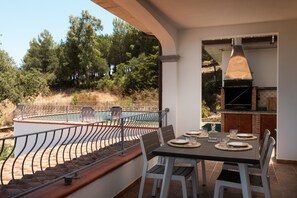 An outdoor dining area with a table set for four, overlooking a swimming pool and a forested hillside. - Villa Certosina by Wonderful Italy (Siniscola)