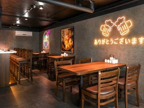 A restaurant interior with wooden tables and chairs, a neon sign, and a framed picture on the wall. - Nice apartment with AC in vibrant Hà Nội city center (Hà Nội)