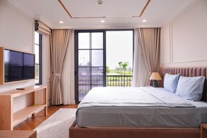 A bedroom with a bed, a TV, a desk, and a balcony with curtains. - Sonasea Villas Collection Residence (Duong To)