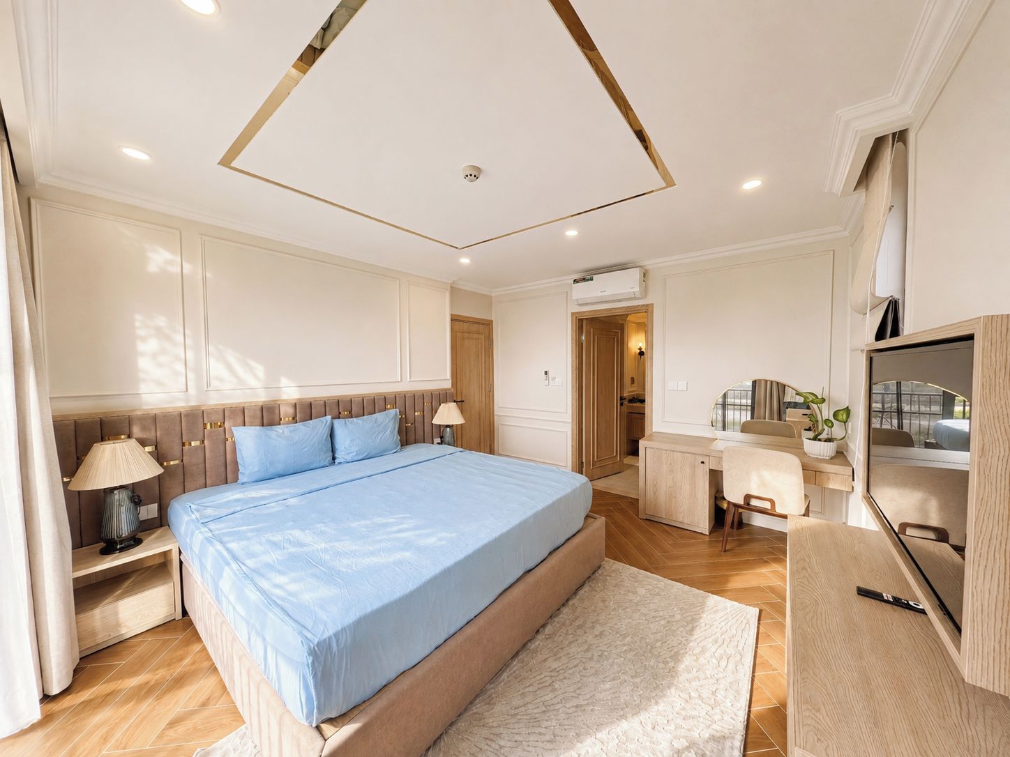 A modern bedroom with a large bed, bedside tables, a desk, and a television.