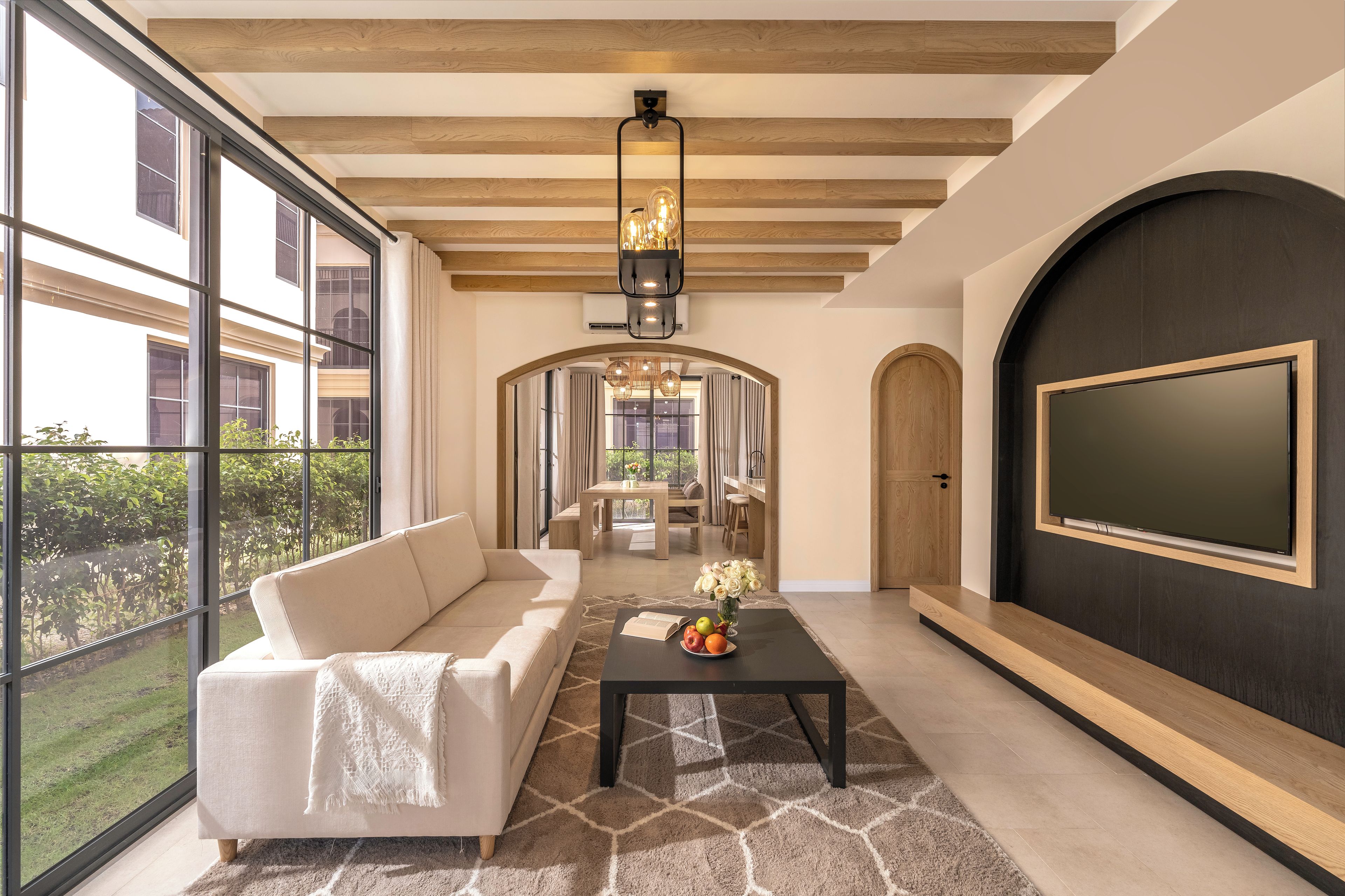 A modern living room with a sofa, a coffee table with fruit, and a TV mounted on the wall.