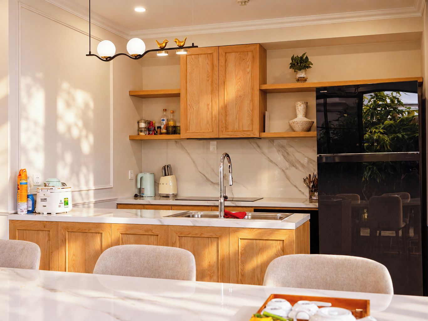 A modern kitchen with wooden cabinets, a marble countertop, a built-in sink, and a black refrigerator.