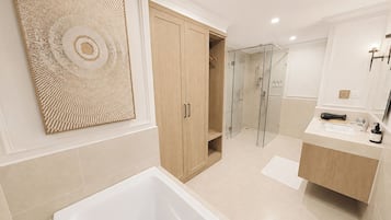 A modern bathroom with a bathtub, a glass shower enclosure, and wooden cabinets.