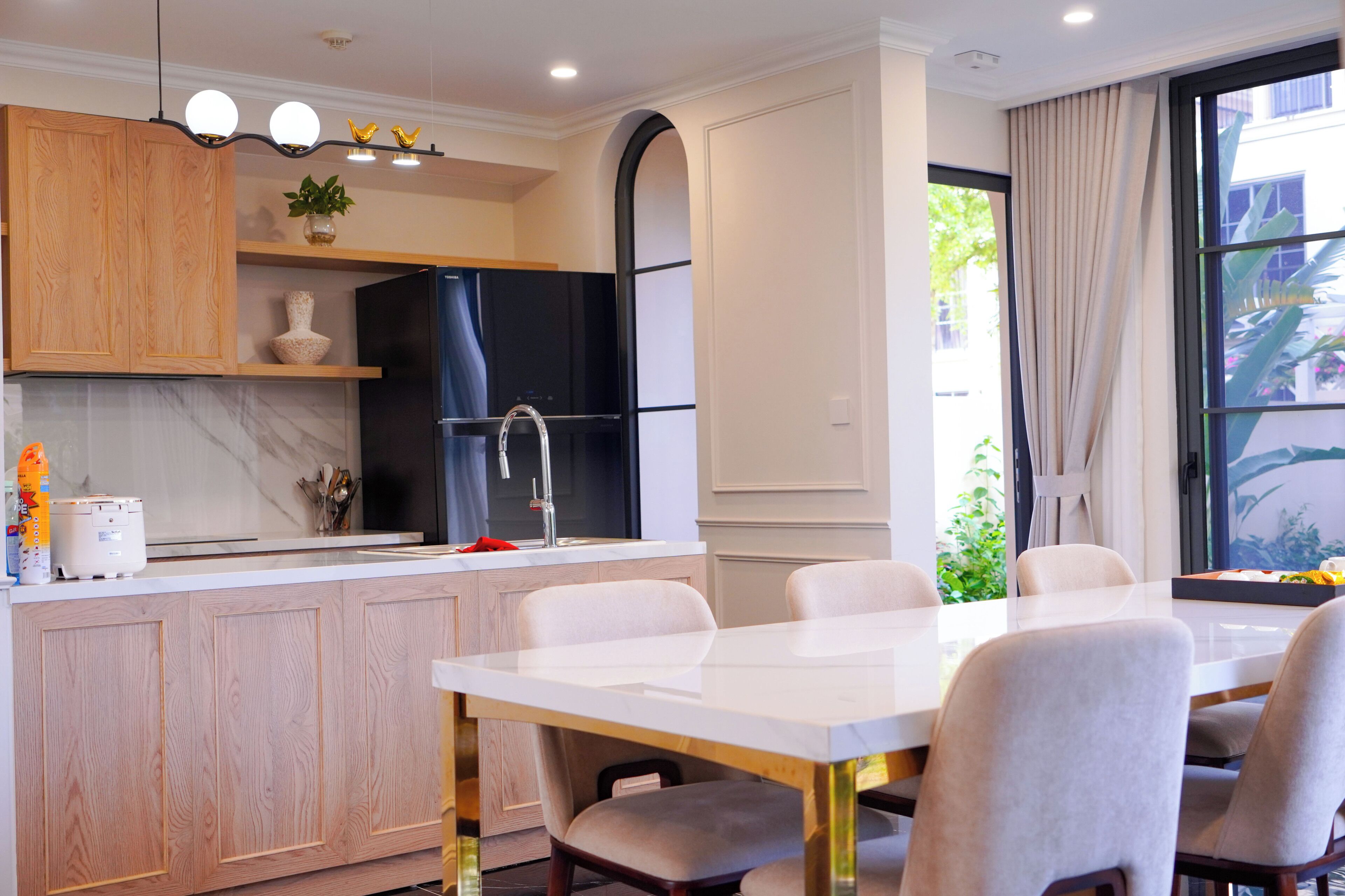 Una cocina moderna con encimera de mármol, armarios de madera y un refrigerador negro.