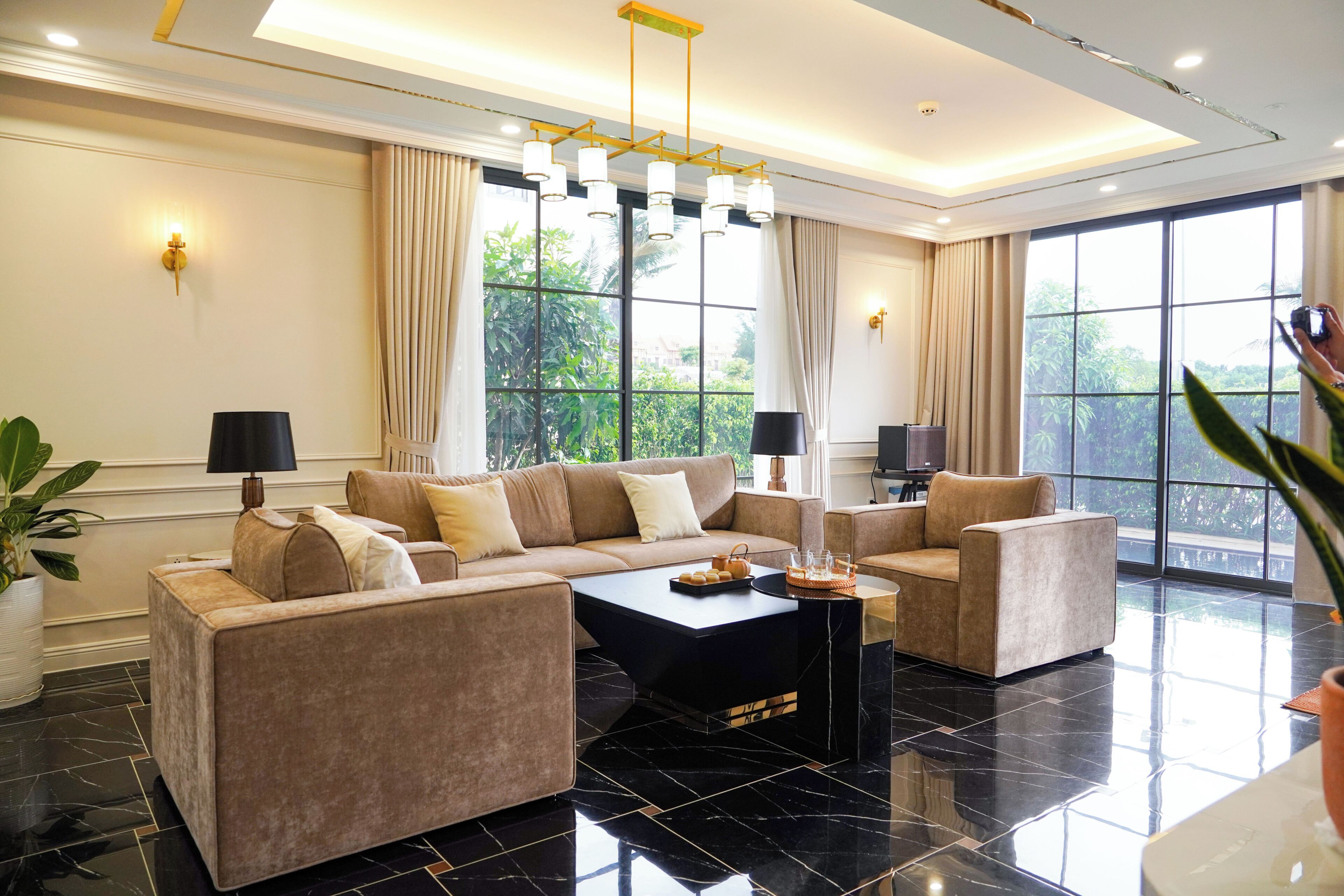 A modern living room with a sectional sofa, two armchairs, a coffee table, and large windows with curtains.