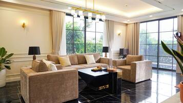A modern living room with a sectional sofa, two armchairs, a coffee table, and large windows with curtains.