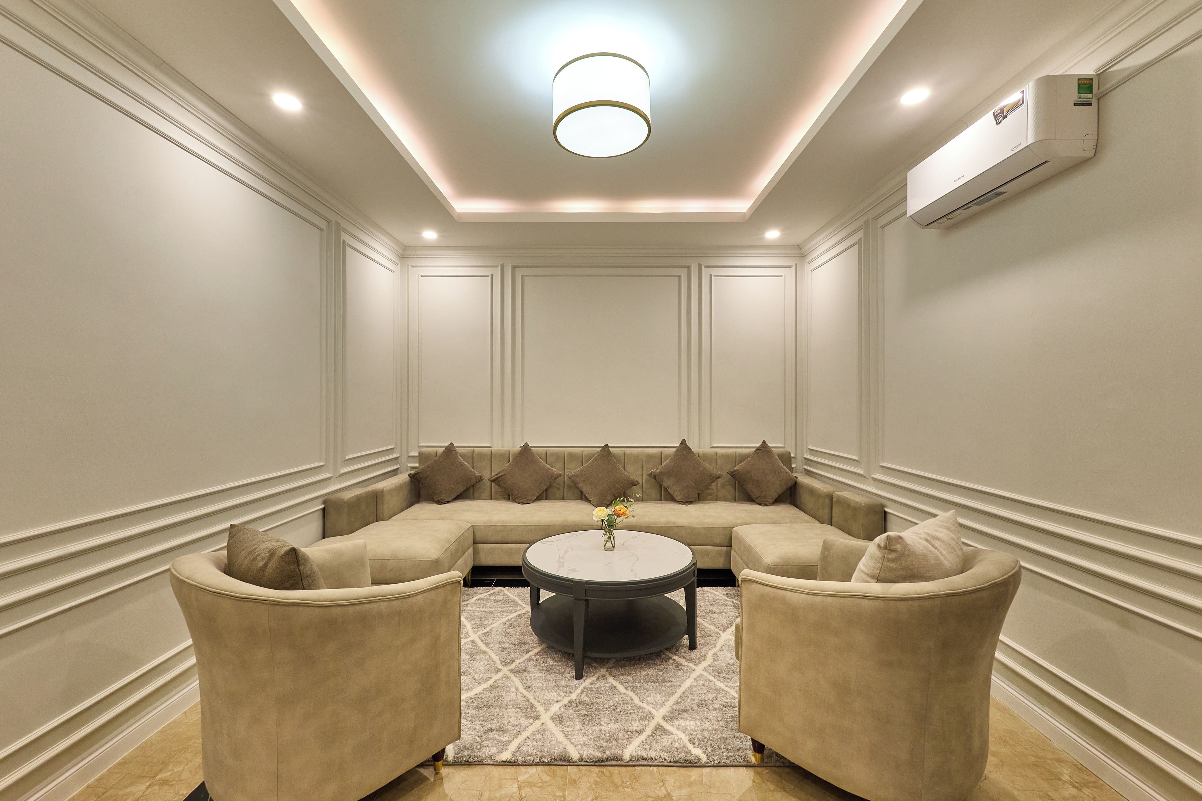 A room with a sectional sofa, two armchairs, a round coffee table, and a patterned rug.