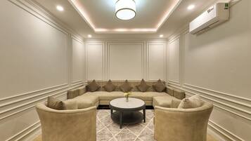 A room with a sectional sofa, two armchairs, a round coffee table, and a patterned rug.