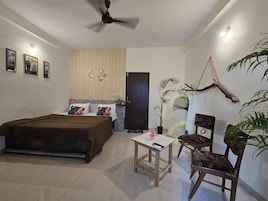 Un dormitorio con cama, una mesita, una silla, un ventilador de techo y una puerta.
