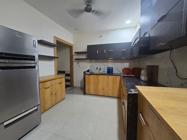 Una cocina con refrigerador, armarios de madera, encimera y ventilador de techo.