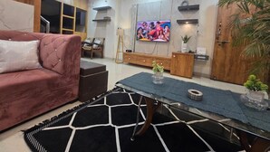 A modern living room with a sofa, a coffee table, a TV, and a plant.