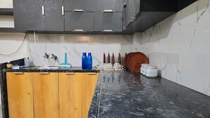 A kitchen with a wooden island, black marble countertop, and a black cabinet above.