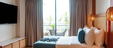 A hotel room with a bed, a TV, a balcony with a view of palm trees, and an air conditioning unit.