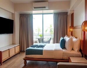 A hotel room with a bed, a TV, a balcony with a view of palm trees, and an air conditioning unit.