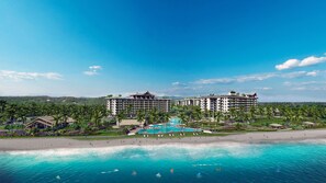 A resort with multiple hotel buildings, a swimming pool, and a beach.
