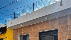 Un edificio moderno con fachada amarilla, una puerta grande negra y una ventana con barrotes.
