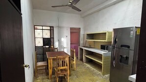 Cocina compacta con refrigerador, microondas y comedor con mesa y sillas.