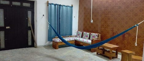 A room with a bed, a sofa, a small table, and a hammock.