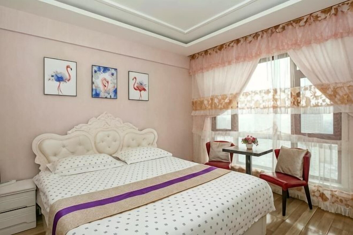 Un dormitorio con una cama grande, una mesita de noche, una silla y tres cuadros colgados en la pared.