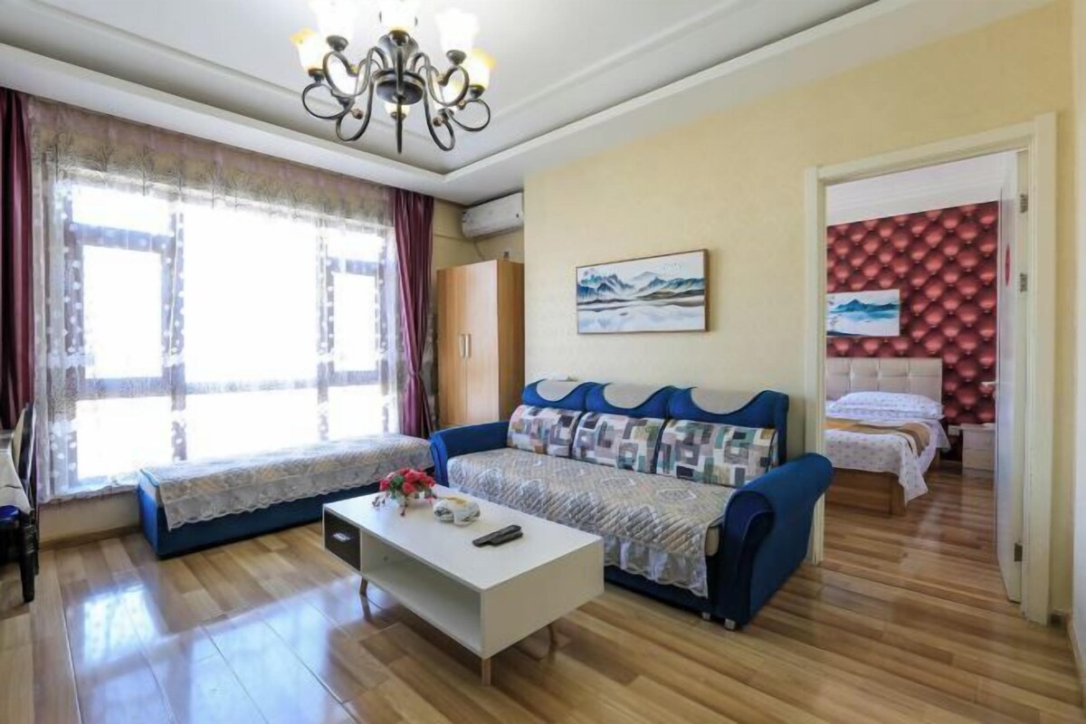 Una sala de estar con sofá, una mesa de centro y una cama al fondo.