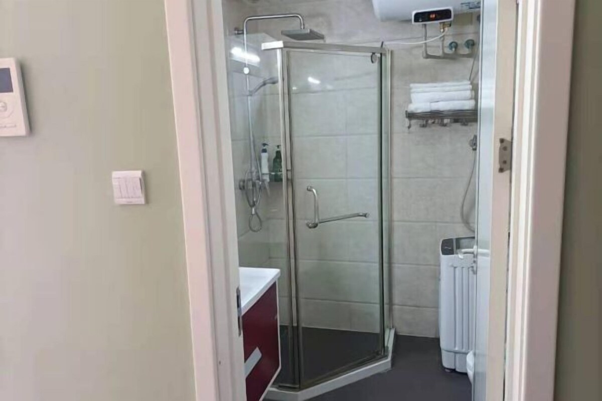 Un box de ducha con paredes de vidrio y un perchero blanco encima.