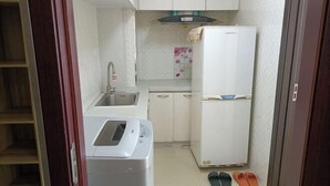 A compact kitchen with a sink, a white refrigerator, and a washing machine. - Hongdou Hotel Apartment (Dalian South China Yihecheng Branch) (Dalian)