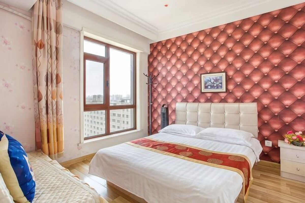 Un dormitorio con una cama grande, una ventana y una pared roja con estampado.