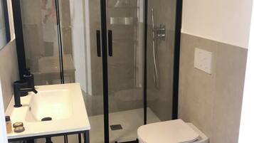 A bathroom with a white sink, toilet, and shower enclosure.