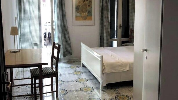 Un dormitorio con cama, una silla, una mesa y un cuadro en la pared.