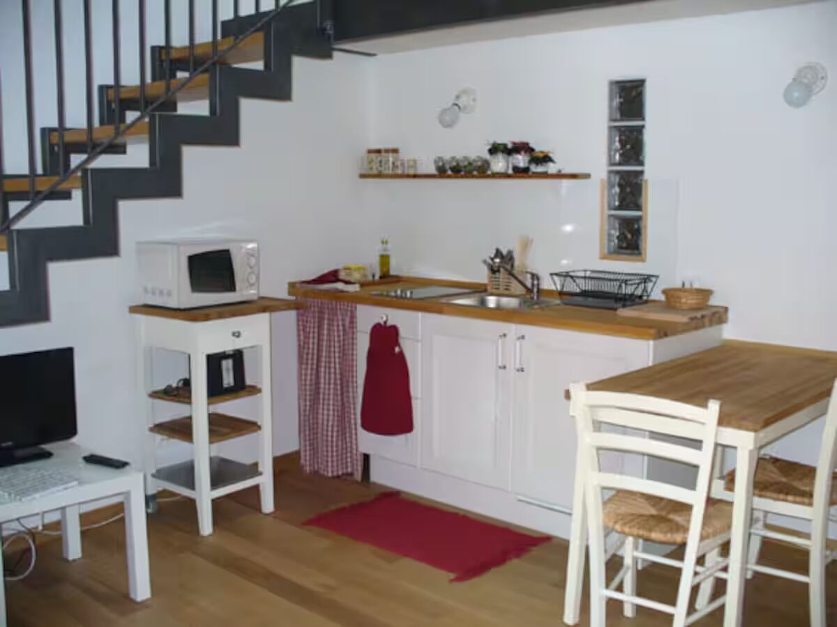 Una cocina funcional con microondas, lavabo y mesa de comedor de madera.