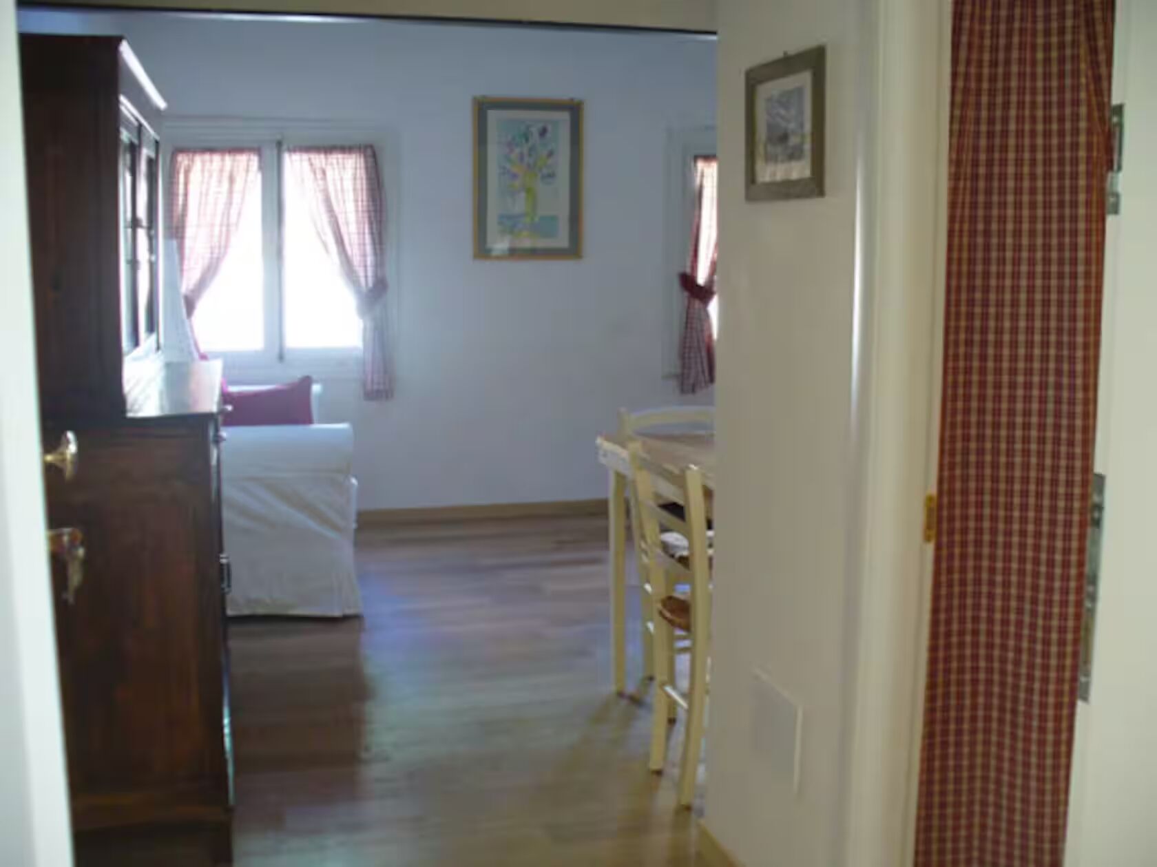 A room with a bed, a chair, a table, and a window with curtains.
