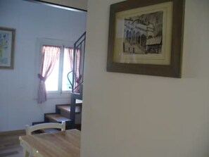 A room with a wooden table, a staircase, and a framed picture on the wall. - Palladio Apartment – Breathtaking View of the Basilica in the Heart of Vicenza (Vicenza)