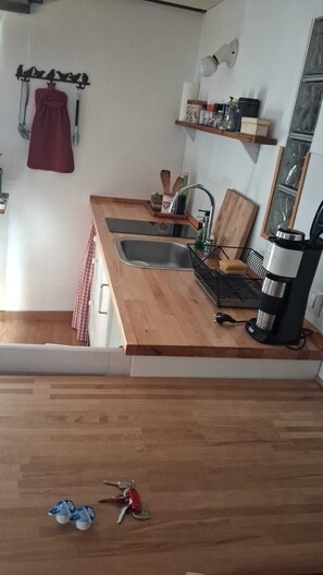 A compact kitchen with a wooden countertop, a sink, a coffee maker, and a shelf with various items. - Palladio Apartment – Breathtaking View of the Basilica in the Heart of Vicenza (Vicenza)