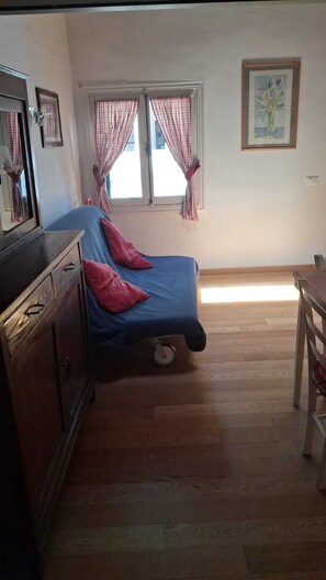 A room with a bed, a dresser, a window with curtains, and a painting on the wall. - Palladio Apartment – Breathtaking View of the Basilica in the Heart of Vicenza (Vicenza)