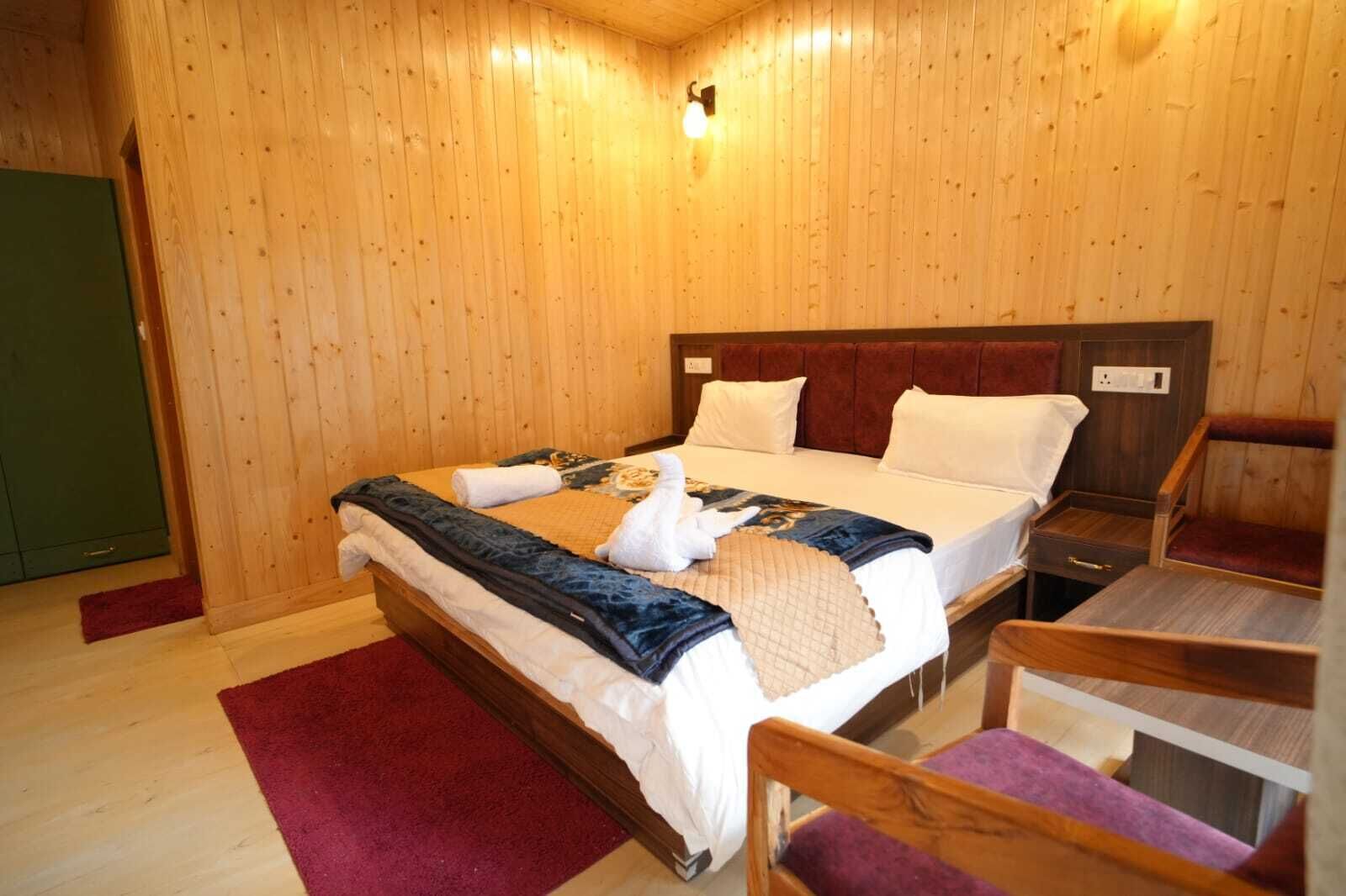 Una stanza con rivestimenti in legno, un letto, un comodino, una sedia e un tavolino.