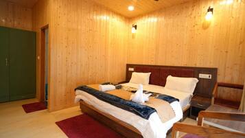 A wooden-paneled room with a bed, a nightstand, a chair, and a green door.