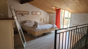 A bedroom with a wooden ceiling, a bed with floral bedding, a nightstand, a window with a red curtain, and a view of the outside. - Bright apartment in the heart of Vicenza's historic center (Vicenza)