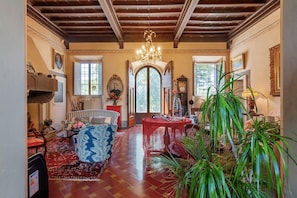 A spacious room with a wooden ceiling, a chandelier, a dining table, and various pieces of furniture. - Villa Il Rossignolo Apartment – Private Garden, Shared Pool & Terrace, Wi-Fi (Grassina)