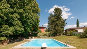 A rectangular swimming pool with a concrete edge, surrounded by grass and trees. - Villa Il Rossignolo Apartment – Private Garden, Shared Pool & Terrace, Wi-Fi (Grassina)