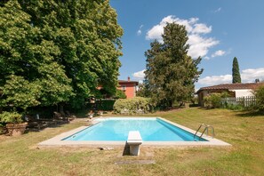 A rectangular swimming pool with a concrete edge, surrounded by grass and trees. - Villa Il Rossignolo Apartment – Private Garden, Shared Pool & Terrace, Wi-Fi (Grassina)