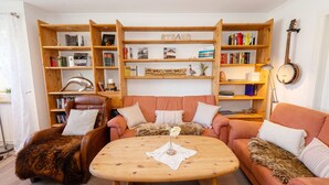 A cozy living room with a sofa set, a coffee table, and a bookshelf filled with books. - Gode Stuv: Cozy vacation rental with a balcony (Büsum)