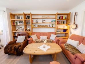 Ein gemütliches Wohnzimmer mit einer Sofagarnitur, einem Couchtisch und einem Bücherregal voller Bücher.