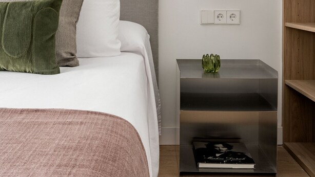 Una camera da letto moderna con un letto, un comodino e una lampada a sospensione rossa.