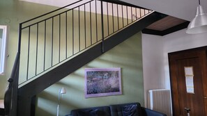 A staircase with a black railing leading to a landing, a framed painting on the wall, a radiator, and a door with a notice. - Bright apartment in the heart of Vicenza with a view of the Basilica Palladiana (Vicenza)
