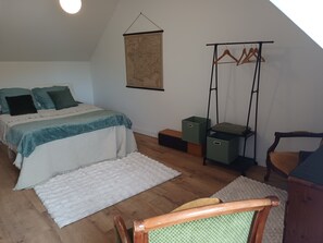 Ein Schlafzimmer mit einem Bett, einer Wandkarte, Aufbewahrungsboxen, einem Sessel und Holzboden.