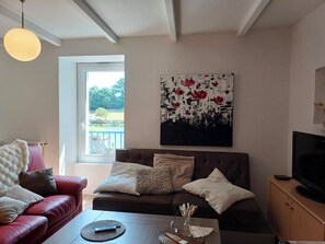 A living room with a sofa, a coffee table, a television, and a painting on the wall.