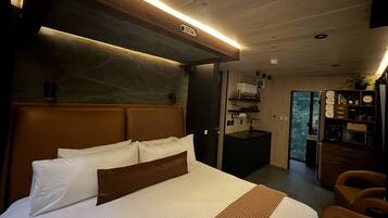 Une chambre moderne avec un grand lit, une tête de lit en bois, un bureau intégré et une vue sur l’extérieur.