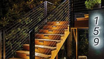 Un escalier moderne avec des rampes en métal, des marches en bois et une plaque indiquant le numéro de l’immeuble, soit le 159.