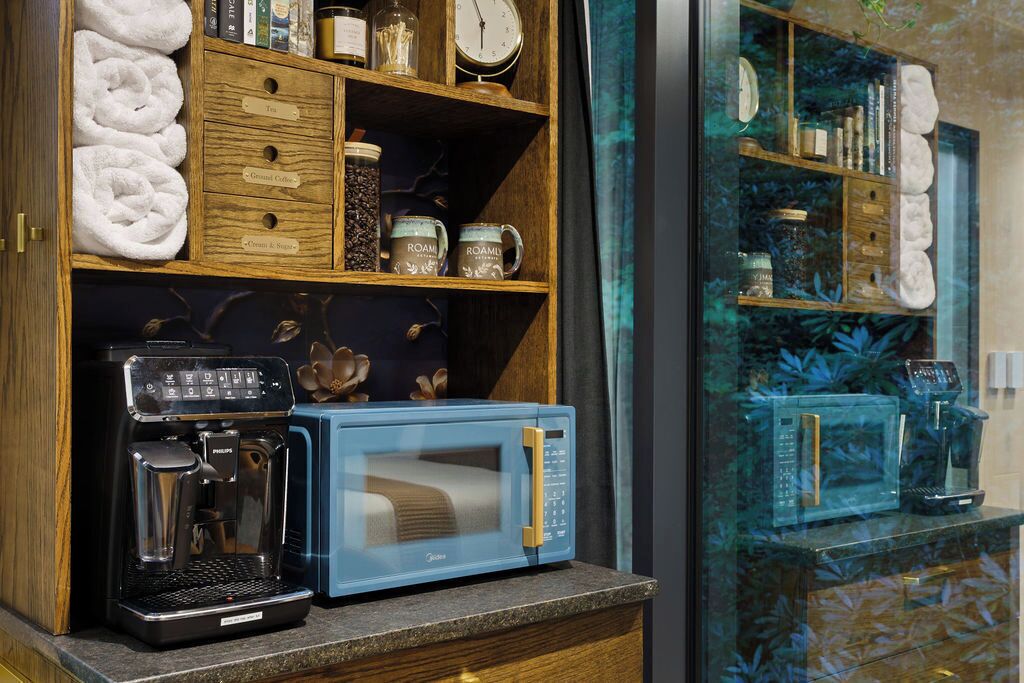 Une petite cuisine équipée d’une machine à café, d’un four à micro-ondes et d’étagères de rangement.